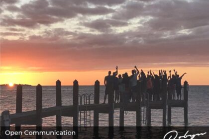 group of people standing on a dock at sunset